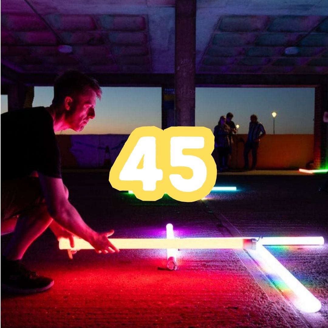 Photo of Kevin in the car park illuminated by colourful lights representing 45 creative hires