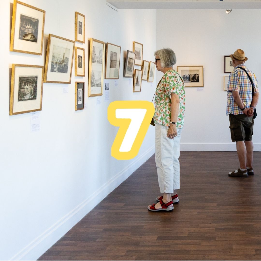 photo of people looking at artwork hung in the gallery representing 7 exhibitions